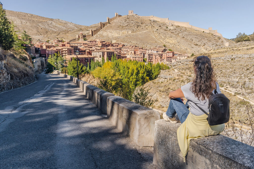 Carina sitter på en mur och tittar på Albarracín.