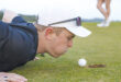 Ung golfare blåser på golfboll.